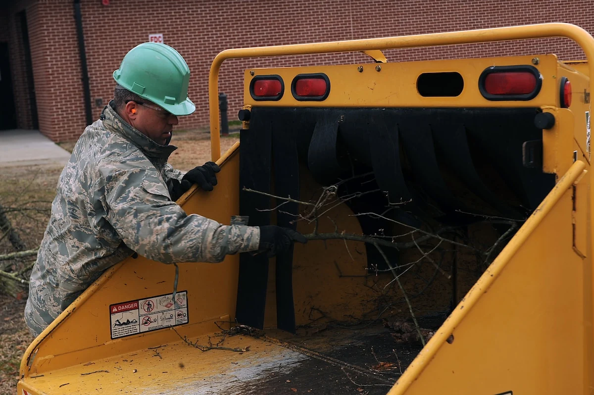 Tree-care worker processing branches at a wood chipper